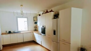 Una cocina con armarios blancos, una encimera, horno empotrado y una planta en maceta.