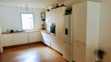 A kitchen with white cabinets, a countertop, a built-in oven, and a potted plant.