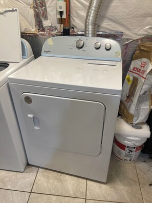 Eine Frontlademaschine von Whirlpool in einem Waschraum mit gefliestem Boden und einer Lüftung.