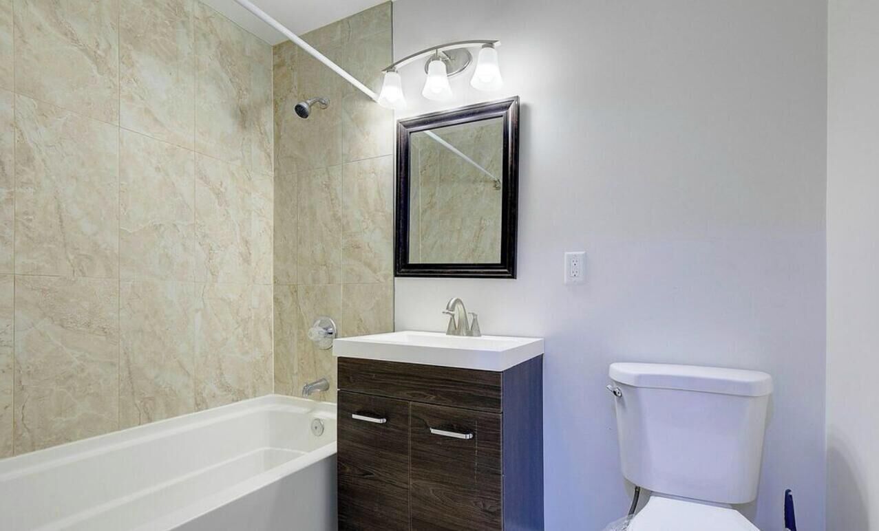 A bathroom with a bathtub, a sink with a mirror above it, and a toilet.