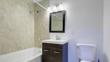 A bathroom with a bathtub, a sink with a mirror above it, and a toilet.