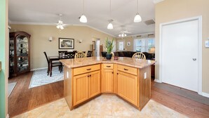 A kitchen with wooden cabinets, a granite countertop, pendant lights, and a ceiling fan. - Twisted Palms - 3/2 Dog Friendly w/ Golf Cart in The Village of Amelia (Amelia, The Villages)
