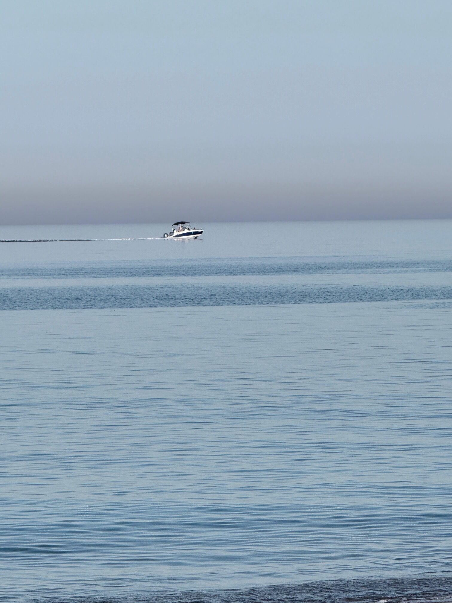 A calm body of water with a single boat in the distance.