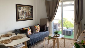 Una sala de estar moderna con sofá, mesa de comedor y un cuadro en la pared.