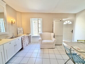 Une cuisine avec un réfrigérateur blanc, une chaise blanche, un évier et une fenêtre donnant sur un beau paysage.