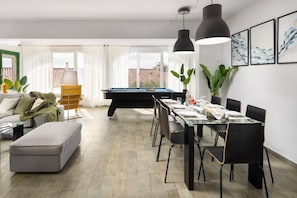 Ein modernes Wohnzimmer mit Billardtisch, Essbereich und einer Couch.