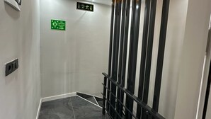 A modern elevator interior with a reflective floor, directional signage, and a safety exit sign. - Ay-Asia Suit (Amasya)