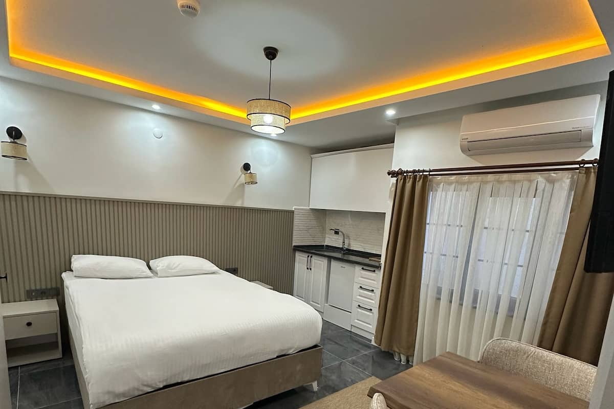 A modern bedroom with a bed, bedside table, and a small kitchenette.