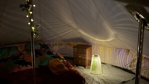A tented room with a bed, a small wooden chest, a lamp, and string lights. - Daisys Meadow Retreat Tent Sleeps 2 With Hot Tub (Ashford)