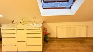 A room with a skylight, a white dresser, and a radiator.