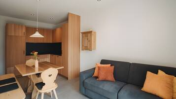 A modern living space with a dining area, a sofa, and a television.
