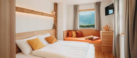 A hotel room with a large bed, a sofa, a TV, and a window with a view.