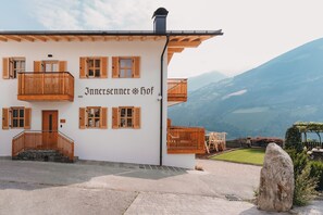 A building with multiple wooden balconies, a stone staircase, and a view of a mountainous landscape. - Apartment 'Morgensonne Innersennerhof' with Mountain View, Wi-Fi and Air Conditioning (Riffian)