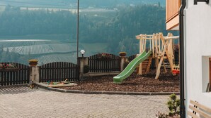 Leikkikentällä on liukumäki ja keinut, ja se on ympäröity puuaitalla. Sieltä on näkymä kauas ulottuviin peltoihin ja rakennuksiin.