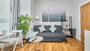 A modern bedroom with a bed, bedside table, lamp, and a view of the sea through a window. - No.1 Princess Green Apartments - UK52036 (Portrush)