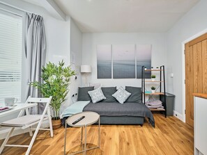 A modern bedroom with a bed, bedside table, lamp, and a view of the sea through a window. - No.1 Princess Green Apartments - UK52036 (Portrush)