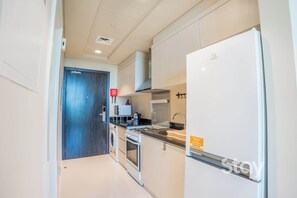 A modern kitchen with a built-in oven, a refrigerator, and a sink. - Resort-Style Studio + Pool & Gym, DAMAC Hills (Dubai)