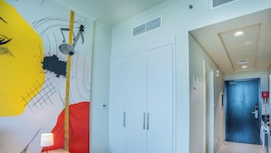 Corredor com um guarda-roupa branco, uma parede de destaque vermelha e uma porta azul que dá para uma área de lavanderia.