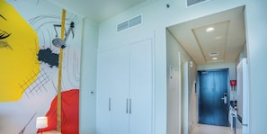 A hallway with a white wardrobe, a red accent wall, and a blue door leading to a laundry area. - Resort-Style Studio + Pool & Gym, DAMAC Hills (Dubai)