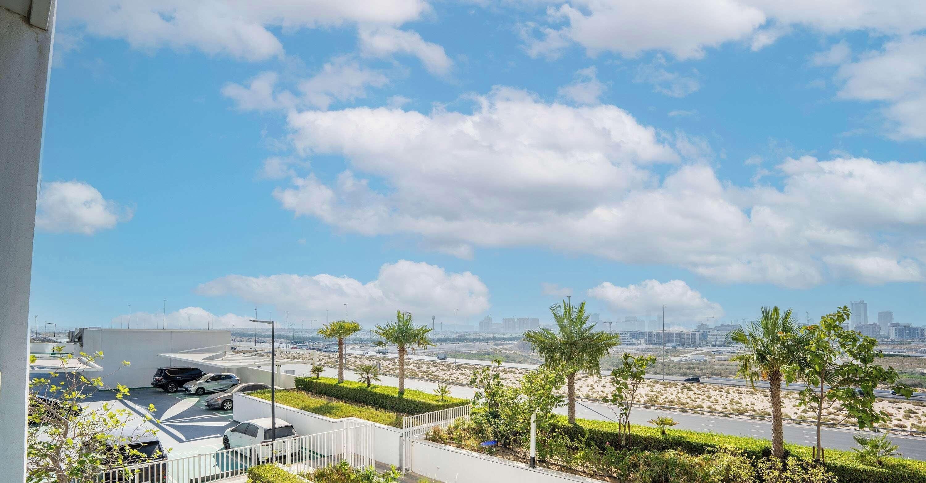 A rooftop with a view of a cityscape, palm trees, and parked cars.