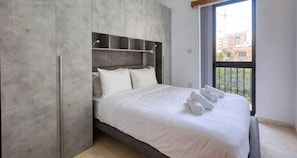 A modern bedroom with a large bed, built-in wardrobe, and a balcony view. - A Premium Apartment in the Heart of Marsaskala (Marsascala MALTA)