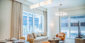 Ein modernes Hotelzimmer mit großem Fenster, einer Couch, einem Esstisch und einem Fernseher.