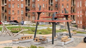 A public square with outdoor seating, a modern sculpture, and a brick building in the background. - Cozy Apartment in Barrow-in-furness (Barrow-in-Furness)