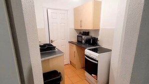 A compact kitchen with a microwave, stove, and cabinets. - Cozy Apartment in Barrow-in-furness (Barrow-in-Furness)
