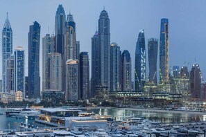 A city skyline with high-rise buildings, a marina with boats, and a waterfront promenade. - Sea-View 1BR + Private Beach, Beach Mansion (Dubai)