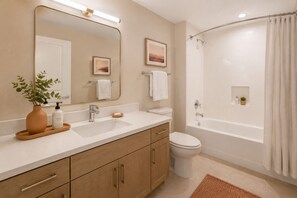 Ein Badezimmer mit Waschbecken, Spiegel, Toilette und Badewanne.