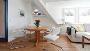 A modern living room with a dining table, two chairs, a sofa, and a coffee table. - House Wendt Apartment 01 (Timmendorfer Strand)