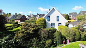 A residential area with houses, well-maintained gardens, and a clear blue sky. - House Wendt Apartment 01 (Timmendorfer Strand)