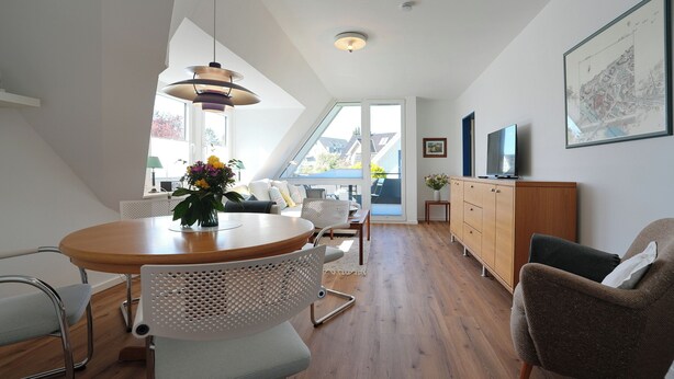 A modern interior with a dining area, a sofa, a TV, and a cabinet. - House Wendt Apartment 01 (Timmendorfer Strand)