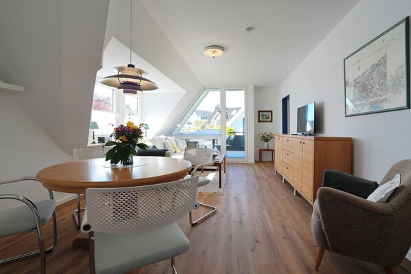 A modern interior with a dining area, a sofa, a TV, and a cabinet. - House Wendt Apartment 01 (Timmendorfer Strand)