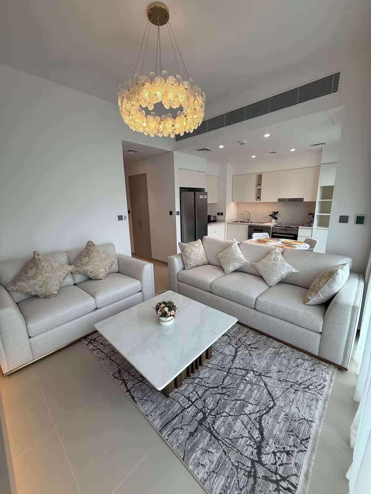 A modern living room with two sofas, a coffee table, and a chandelier.