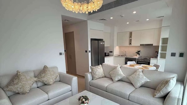 A modern living room with two sofas, a coffee table, and a chandelier. - Sun-Drenched 3BR Garden Villa, Arabian Ranches (Dubai)
