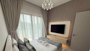 A modern bedroom with a large bed, a flat-screen TV mounted on the wall, and a wardrobe. - Sun-Drenched 3BR Garden Villa, Arabian Ranches (Dubai)