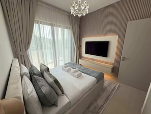 Ein modernes Schlafzimmer mit einem großen Bett, einem flachbildfernseher an der Wand und einem Kleiderschrank.