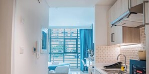 A modern kitchen with a large window, a dining area with a white table and chairs, and a visible balcony. - Live on the Palm: Studio + Pool, Seven Palm (Dubai)