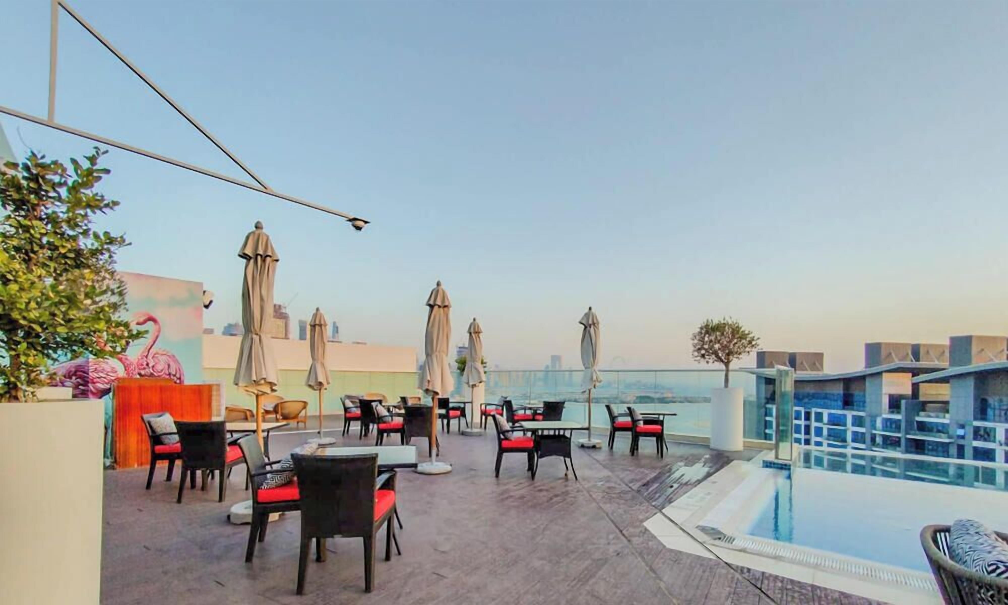 Un bar situé sur le toit, avec une terrasse, des parasols et une piscine.