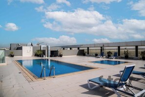 Ein Poolbereich auf dem Dach mit zwei Pools, Liegestühlen und Topfpflanzen.