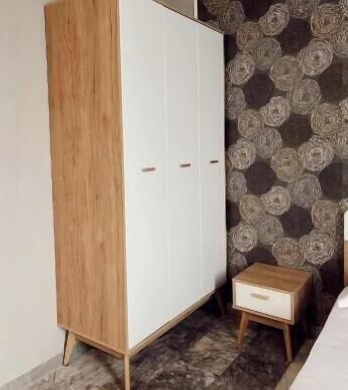 A wardrobe with a wooden finish and a small drawer unit.