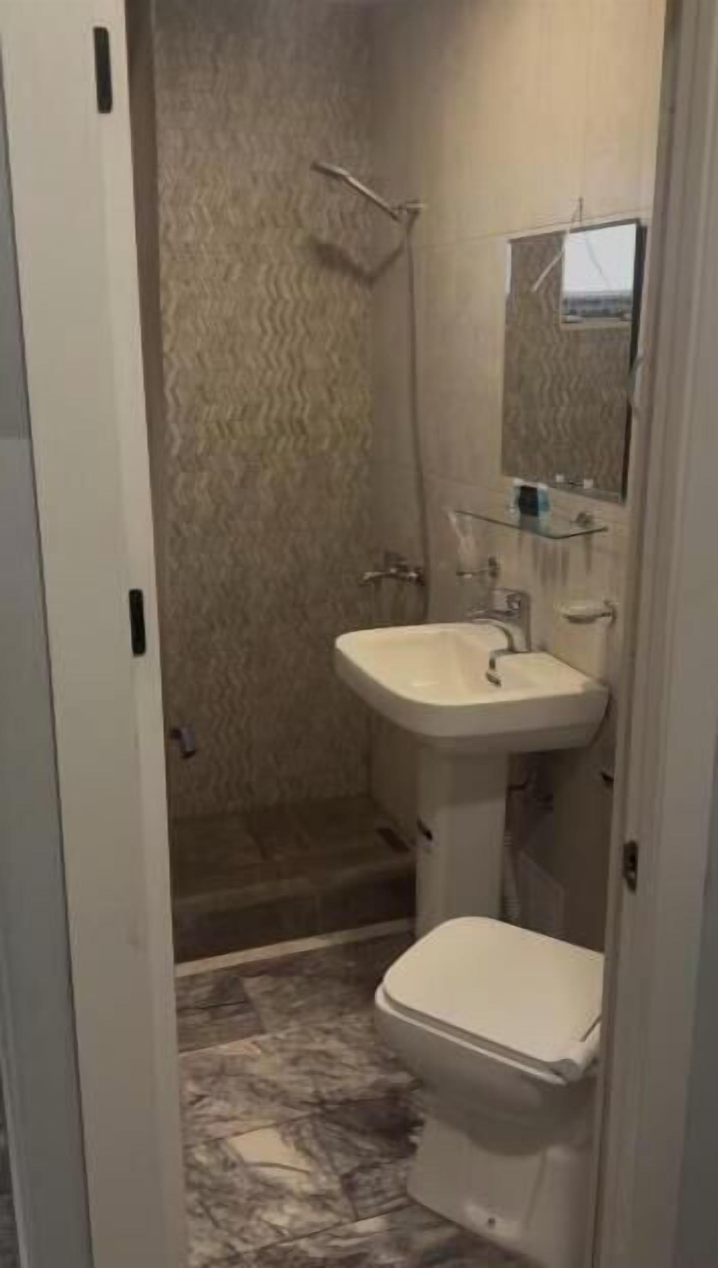 A bathroom with a shower, sink, and toilet.