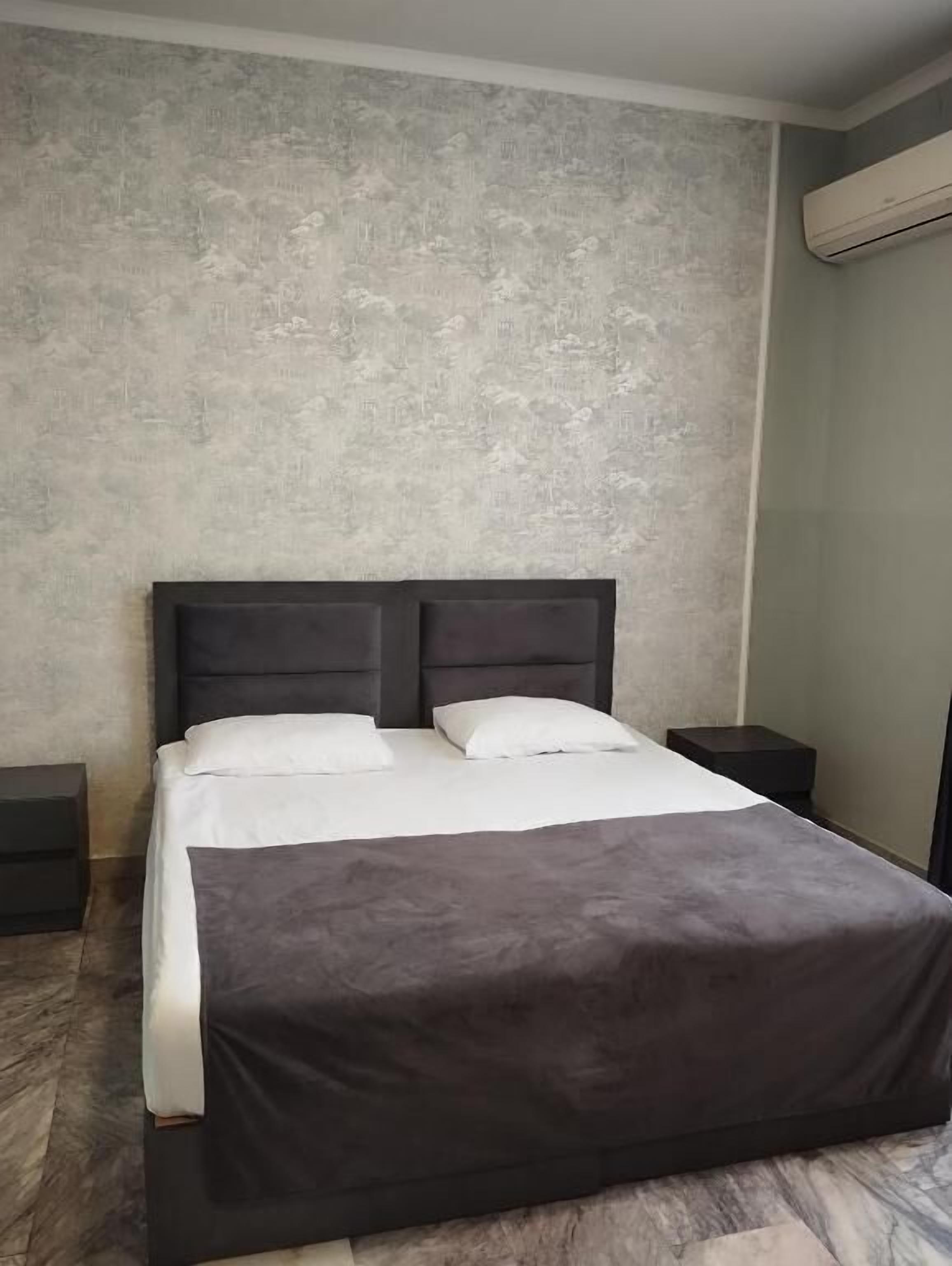 A bed with a dark headboard, white bedding, and a marble floor.