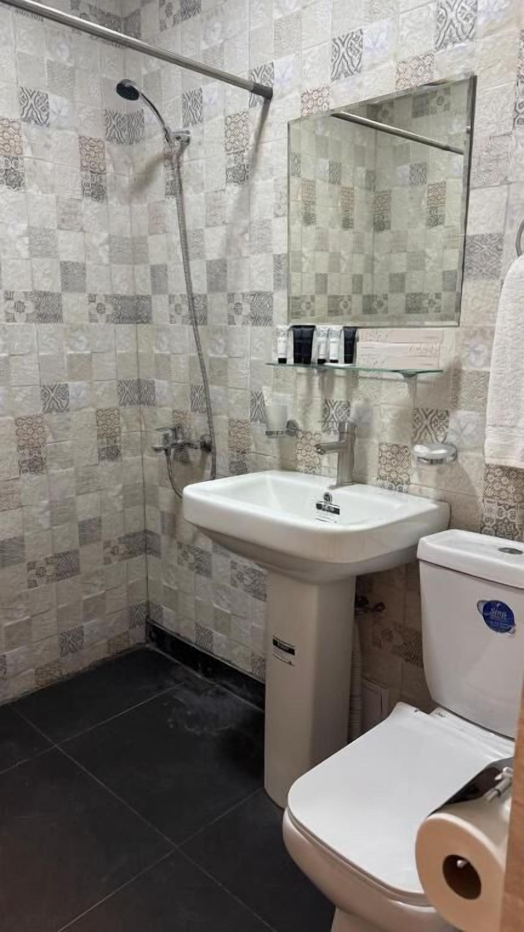 Un baño con ducha, lavamanos, inodoro y espejo.