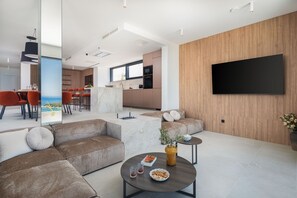 Ein modernes Wohnzimmer mit einer Couch, einem Couchtisch und einem flachbildfernseher, der an einer Holzwand angebracht ist.