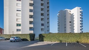 Ein Parkplatz mit zwei weißen Mehrfamilienhäusern im Hintergrund.