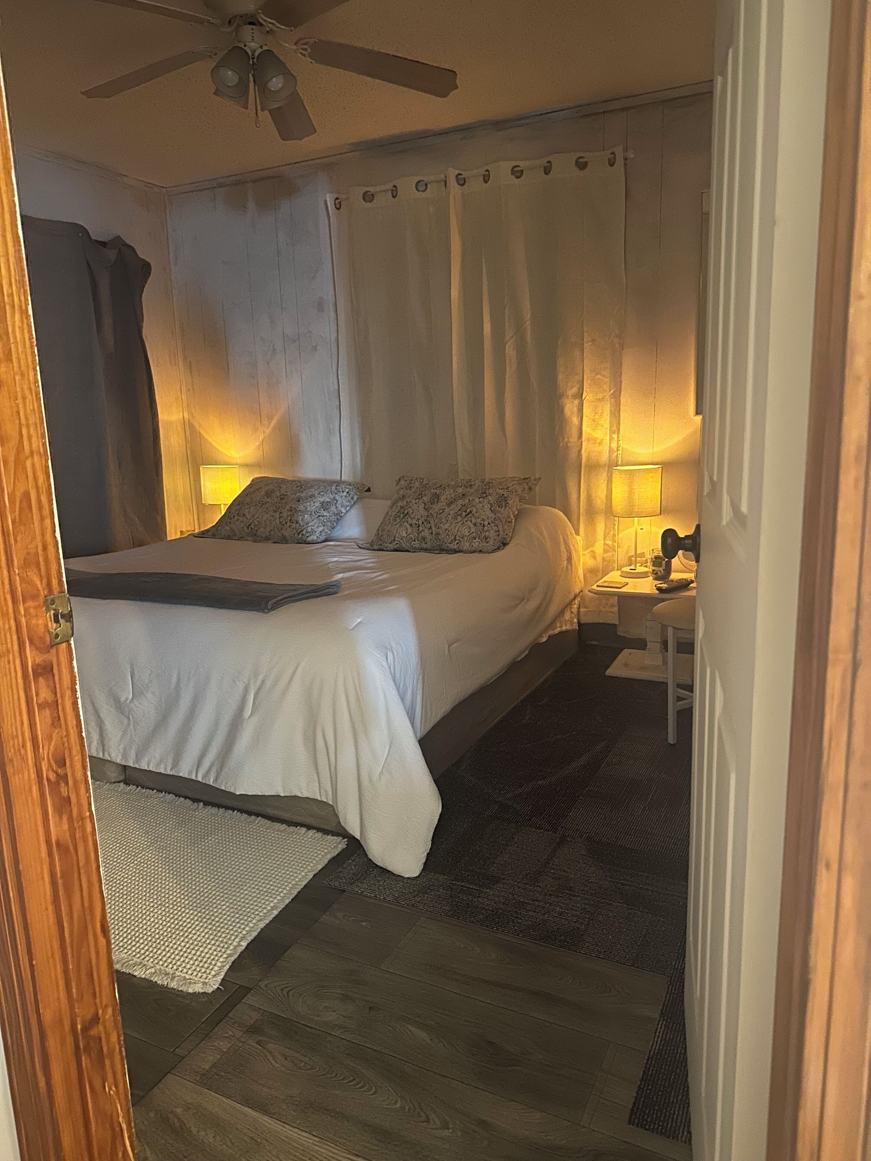 Camera da letto con un letto, lampade da comodino, una ventola a soffitto e una porta.
