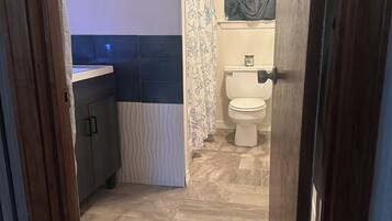 Une salle de bain comprenant des toilettes, un lavabo et un espace douche.