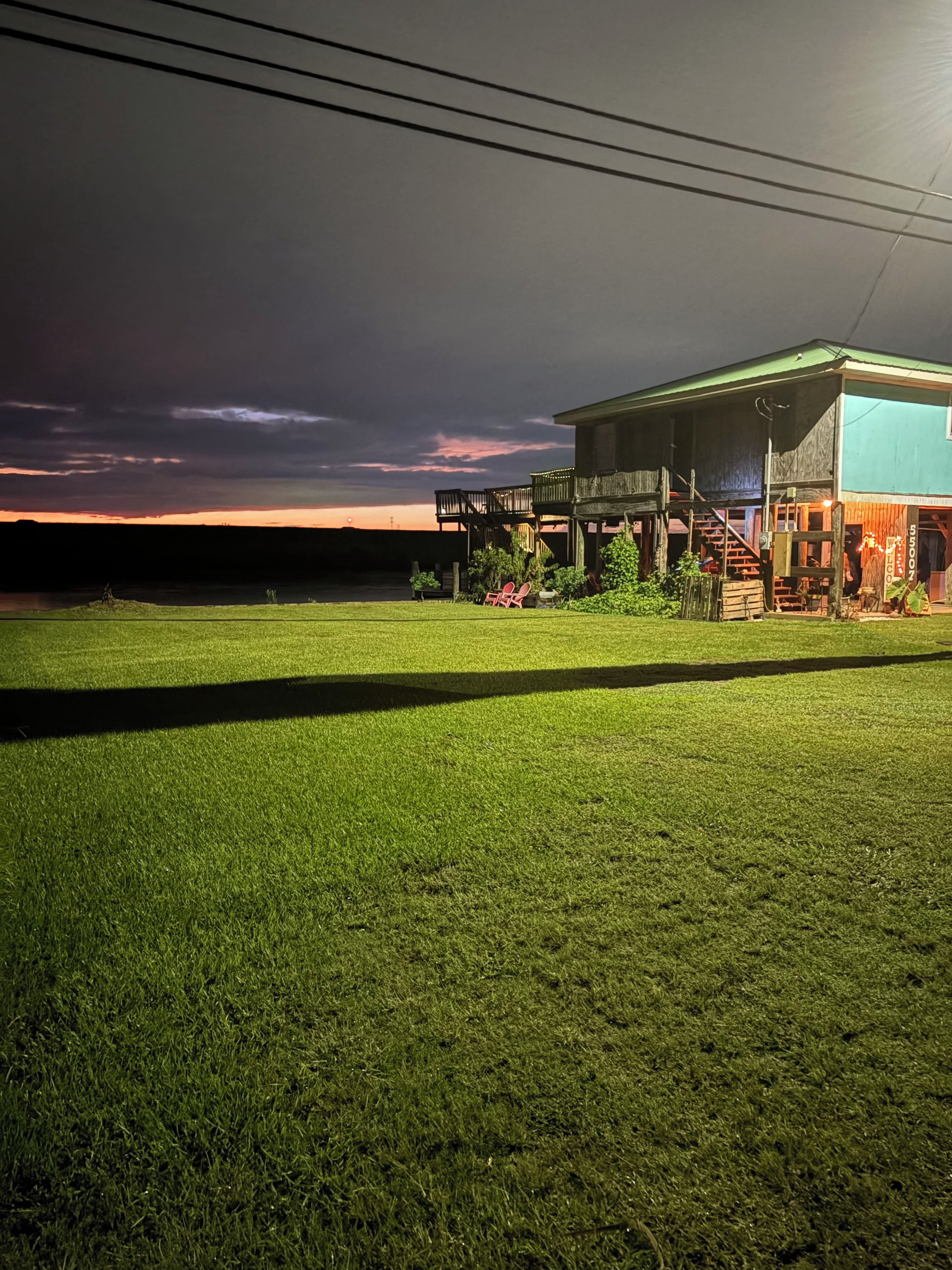 A grassy area in front of a building with a porch and a sign that reads 'SILVER'.